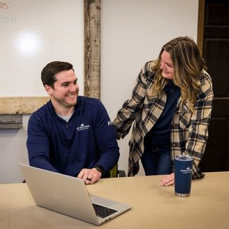 Two animal health warehouse team members in a meeting room looking at orders on a computer.