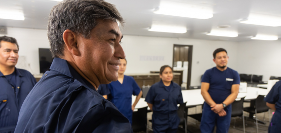 A group of farm workers standing in a meeting room.