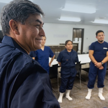 A group of farm workers standing in a meeting room.