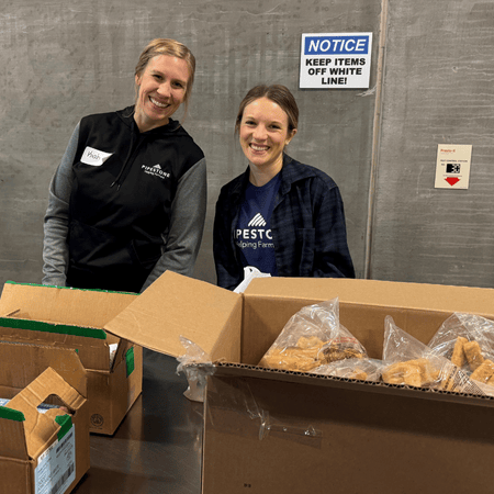 Two pipestone team members help pack boxes with pork meals to donate through the Meat the Need program.