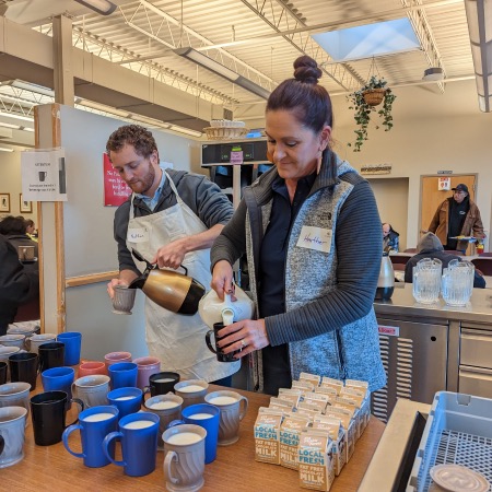 Two pipestone volunteers pour coffee and milk into cups.