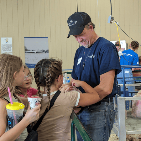 A pipestone volunteer holds a piglet for children to see and touch at the fair.