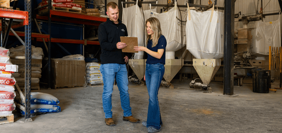 Two FarmBooks team members stand in a warehouse looking over inventory and financials for the farm.