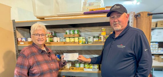 A pipestone team member hands a check to a food shelf that is local to a pipestone sow farm.
