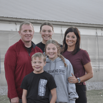 The Weber family standing in front of a swine barn.