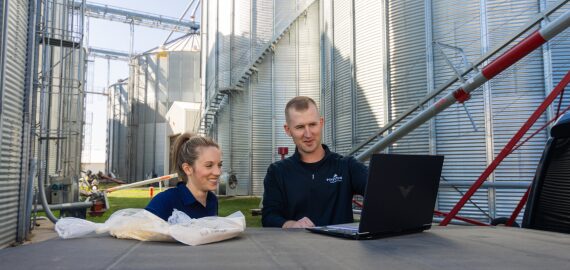 A nutritionist and financial advisor review sow nutrition data on a laptop.