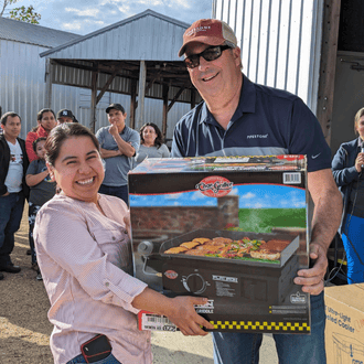 A pipestone team member hands a griddle to a woman as a prize at a team picnic.