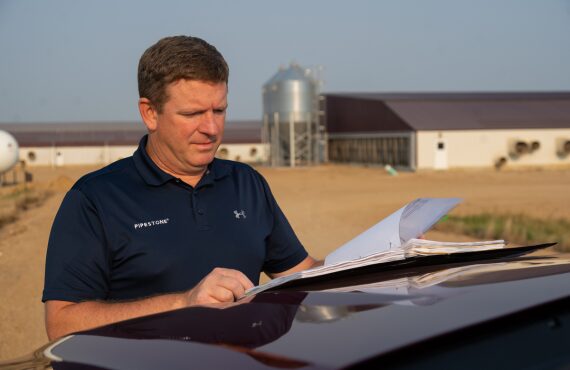 A pipestone research team member stands outside of a swine barn and looks at data that has been collected.