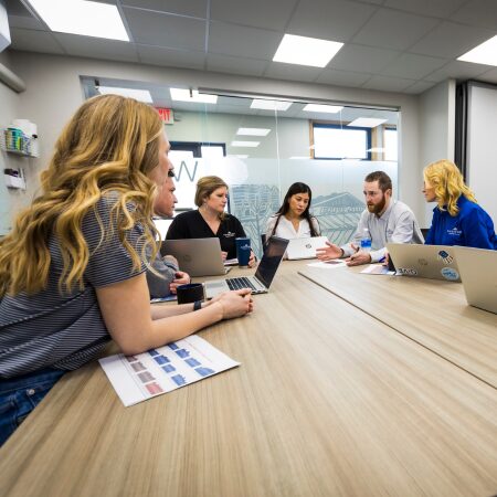 A group of FarmBiz team members sit in a meeting room to create a farm plan for a swine producer.