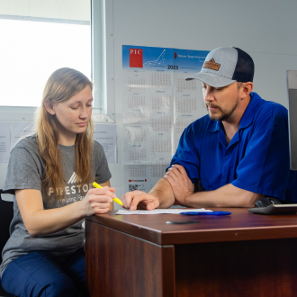 Two team members review pig production data in an office.