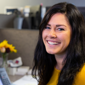 A swine health warehouse office worker sits at her desk and smiles.