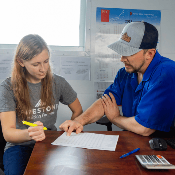 A supervisor reviews production results from a sow farm with a new hire.