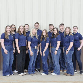 A group of interns in matching shirts pose for a photo.