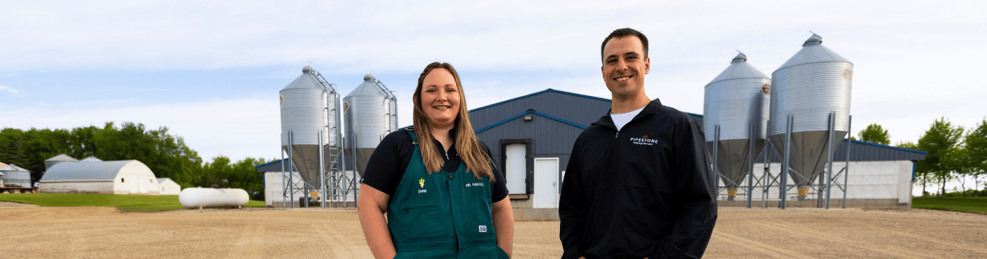 A swine veterinarian and a production consultant stand outside of a grow finish barn.