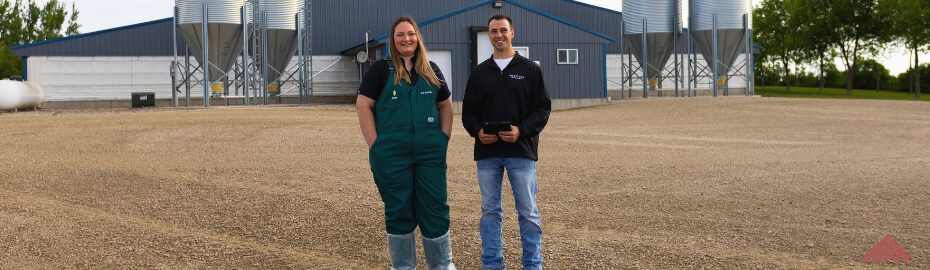 A swine veterinarian and production consultant stand outside of a wean-to-finish barn.