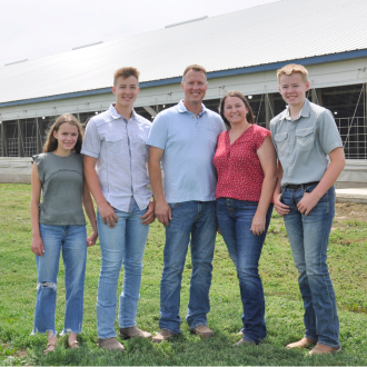 The Hanson family standing in front of a swine barn.