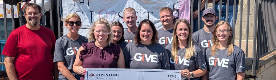 A group of team members in GiVE shirts hold a check to donate funds to the Foster Network for supplies for foster children.