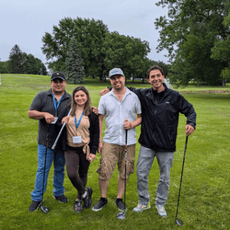 A group of Pipestone team members pose on a golf course.