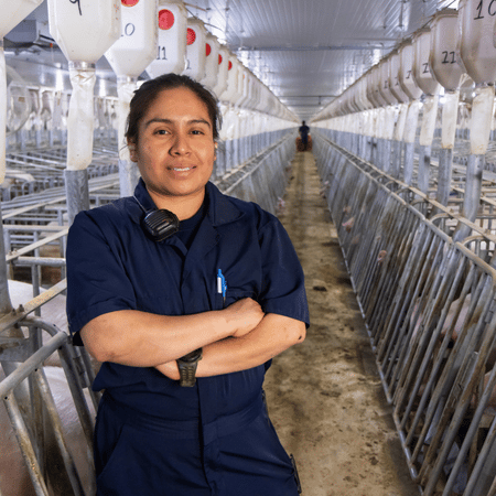 A swine technician stands with her arms crossed in a sow farm.