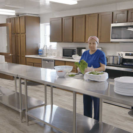 A sow farm office coordinator stands in a clean kitchen preparing lunch for the team.