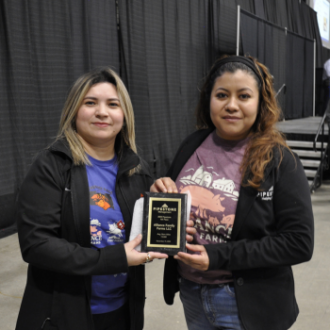 A supervisor presents a swine production award to a sow farm site manager.