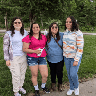 A group of women pose together outside at a picnic.