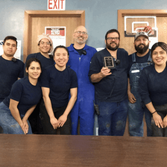 A sow farm team poses with a production award plague in their farm.