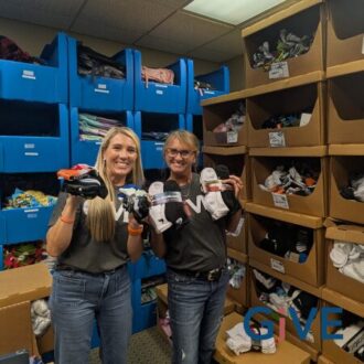 Two Pipestone team members hold up socks donated by the team for the children at the Foster Network.