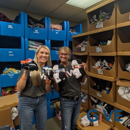 Two Pipestone team members hold up socks donated by the team for the children at the Foster Network.